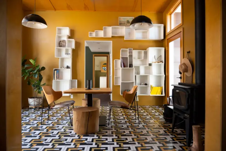 Modern room with geometric floor, unique shelving, wooden furniture, and a warm color palette.
