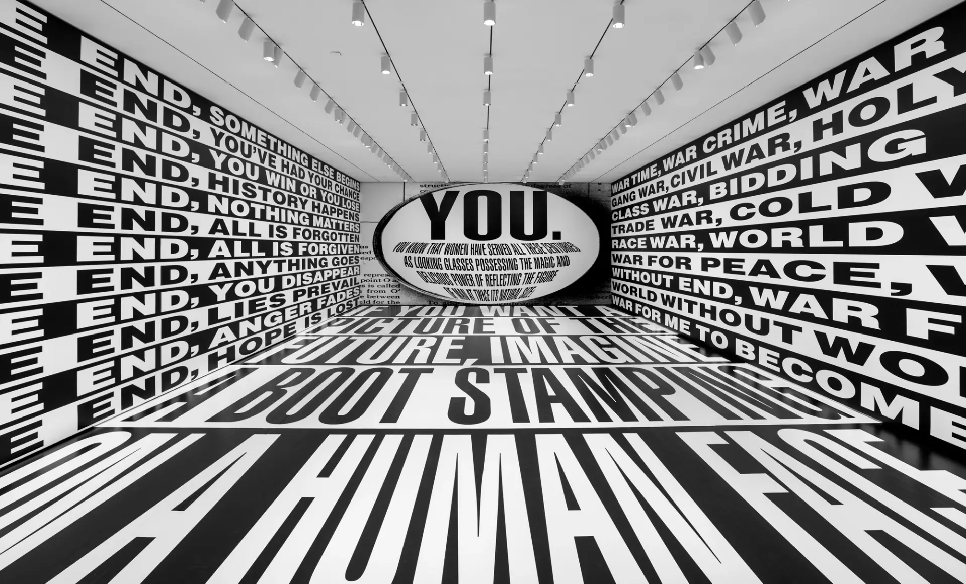 An art installation room featuring large white text on a black background, covering both the floor and the walls.