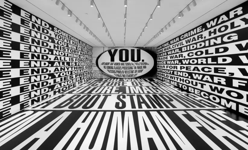 An art installation room featuring large white text on a black background, covering both the floor and the walls.