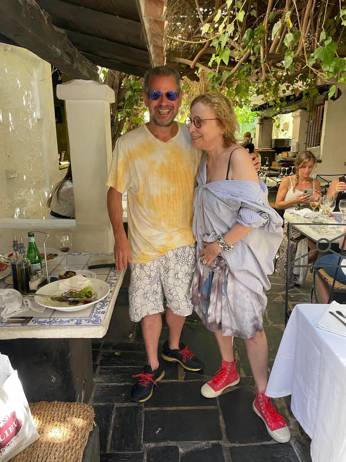 Two people stand side by side in a restaurant, one facing the camera.