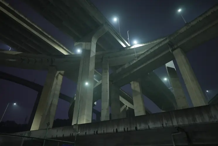 A nighttime photo is captured from a frog’s perspective, showcasing a towering infrastructure of roads in heights. Strikin...