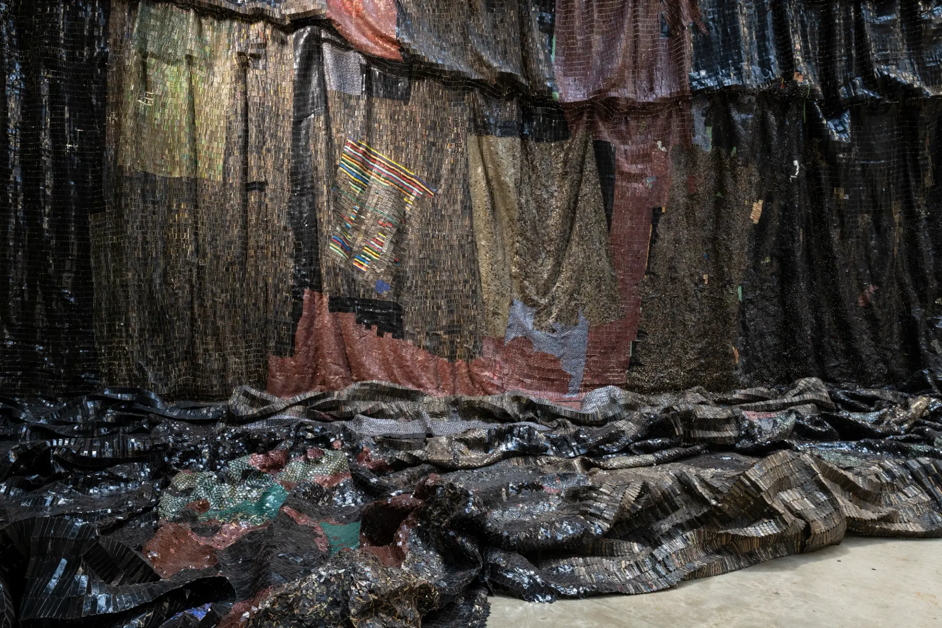 Textured art installation with dark, woven materials and colorful accents creating a visually rich tapestry.