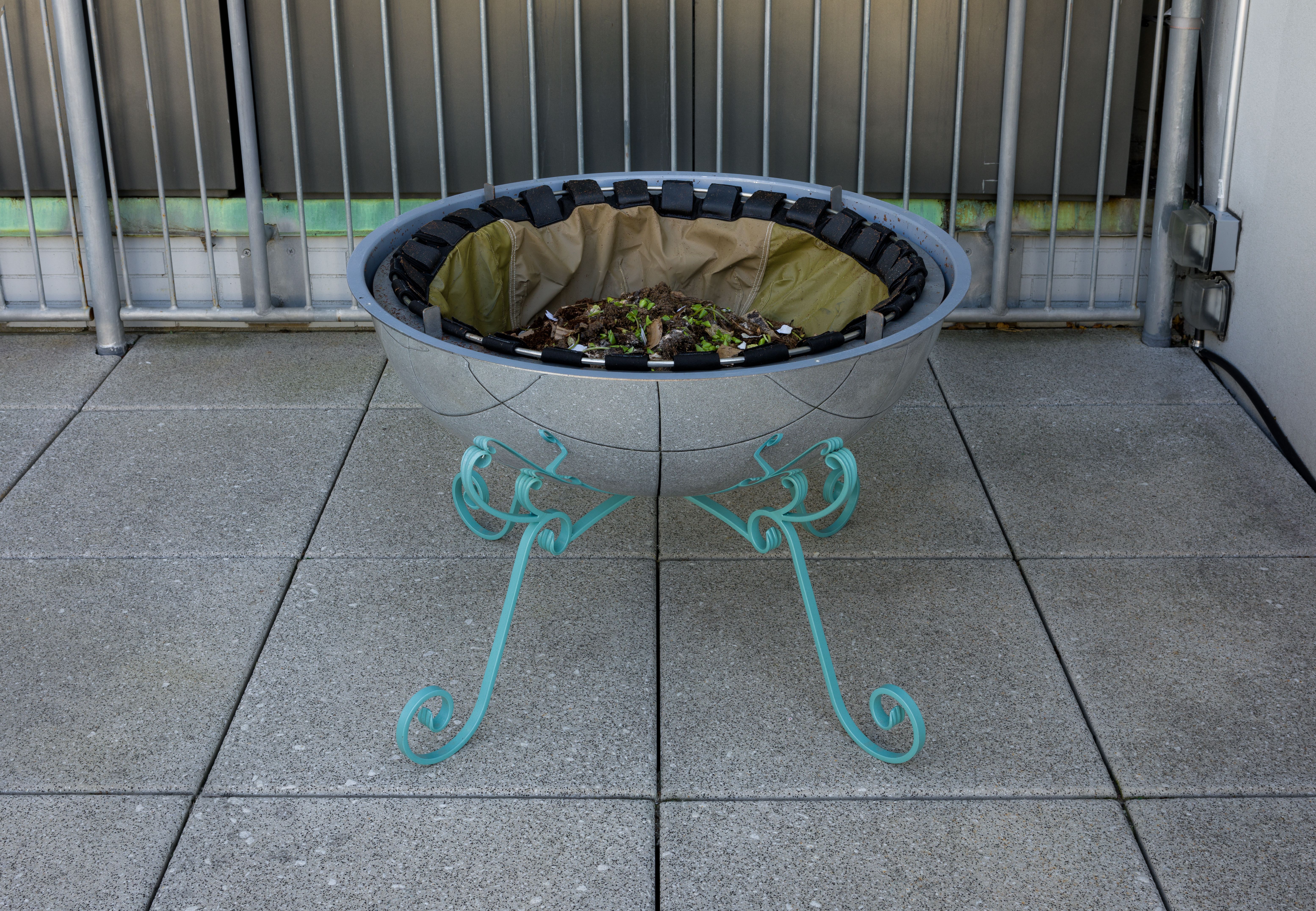 The same hemispherical sculpture shown open, revealing soil and organic material inside.