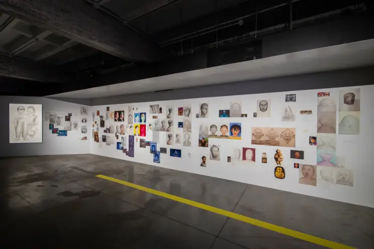 Gallery wall filled with varied portraits and multimedia art pieces.