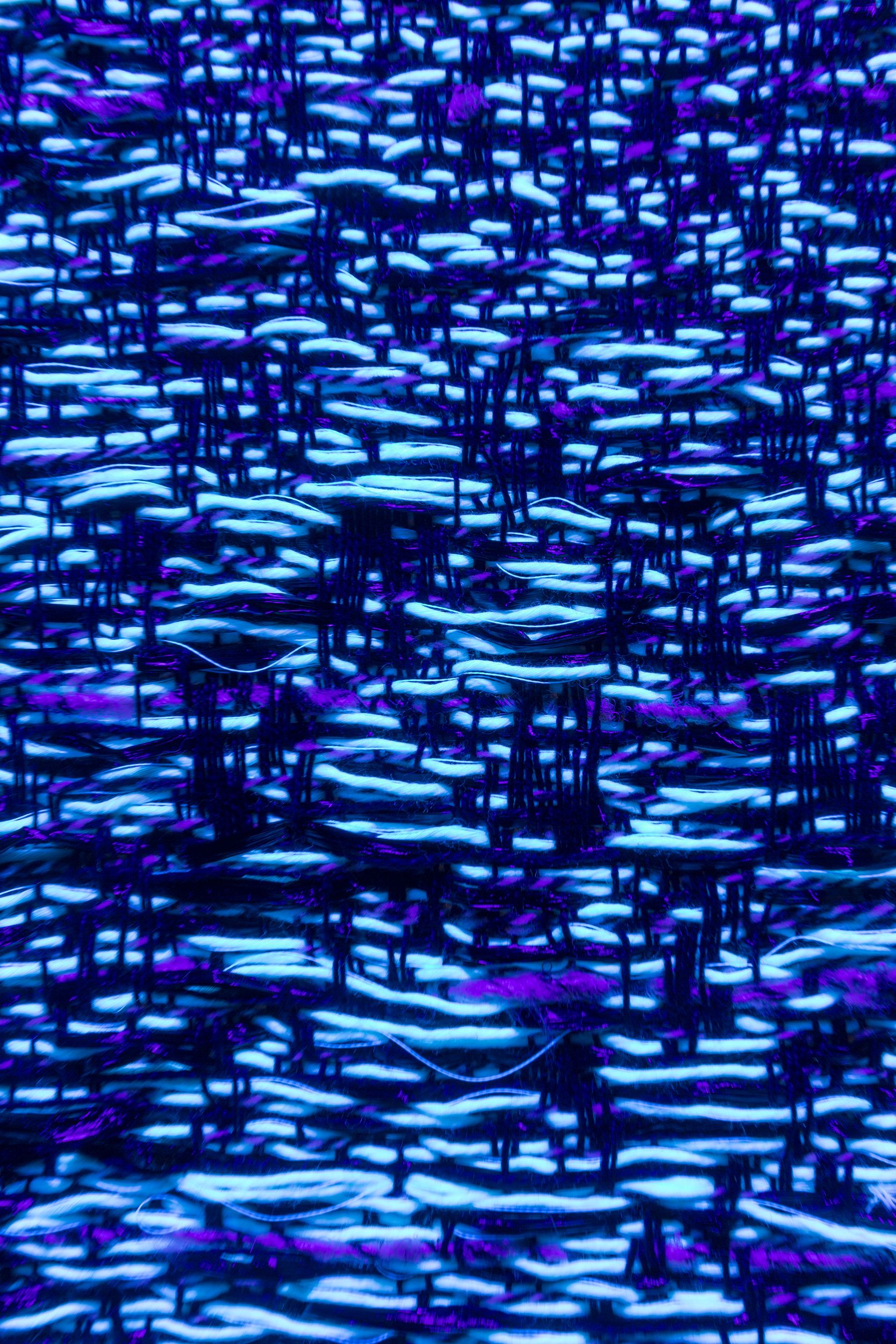 A close-up view of woven fabric with blue and purple threads forming intricate patterns.