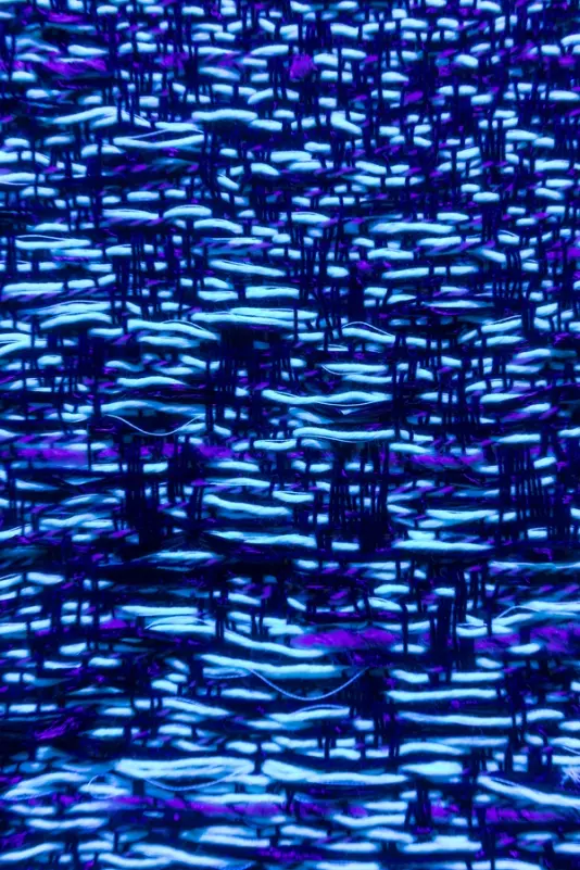 A close-up view of woven fabric with blue and purple threads forming intricate patterns.
