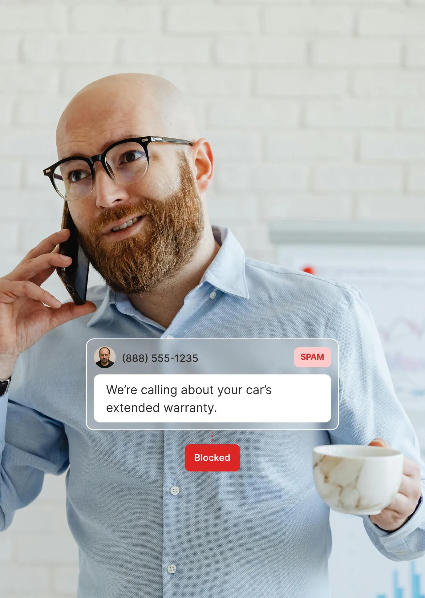 A man on the phone receives a spam warranty call that the spam blocking service flags and blocks automatically.
