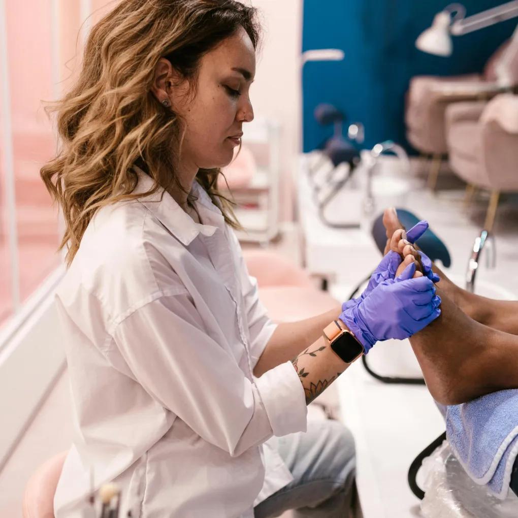 Nail technician performing pedicure service while spa and salon answering service handles client bookings