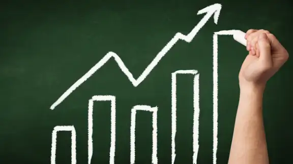 A grown ups hand drawing chart with exponentially growing arrow on green chalkboard.jpeg