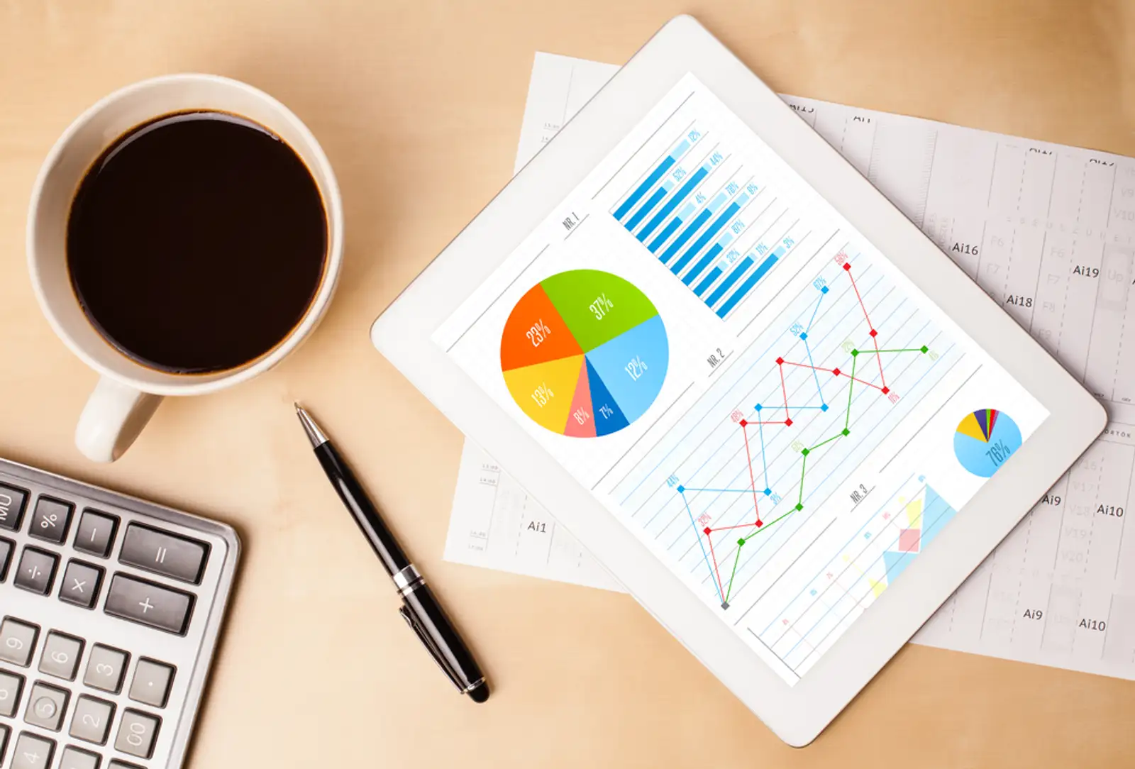 Workplace with tablet pc showing charts and a cup of coffee on a wooden work table close-up-1.jpeg