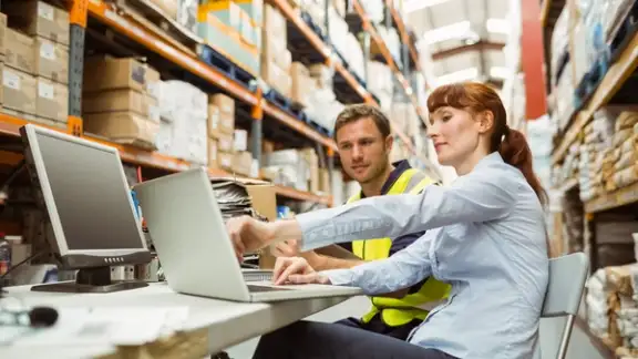 Warehouse worker and manager looking at laptop in a large warehouse.jpeg