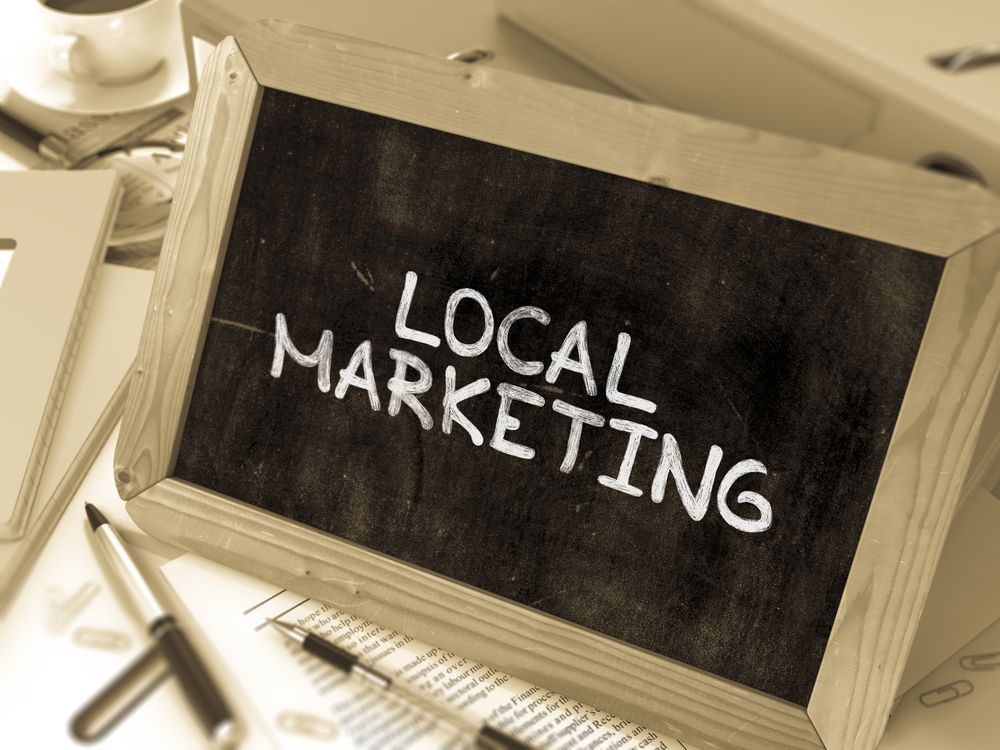 Local Marketing - Chalkboard with Hand Drawn Text%2c Stack of Office Folders%2c Stationery%2c Reports on Blurred Background. Toned Image. 3d Render..jpeg