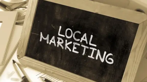Local Marketing - Chalkboard with Hand Drawn Text%2c Stack of Office Folders%2c Stationery%2c Reports on Blurred Background. Toned Image. 3d Render..jpeg