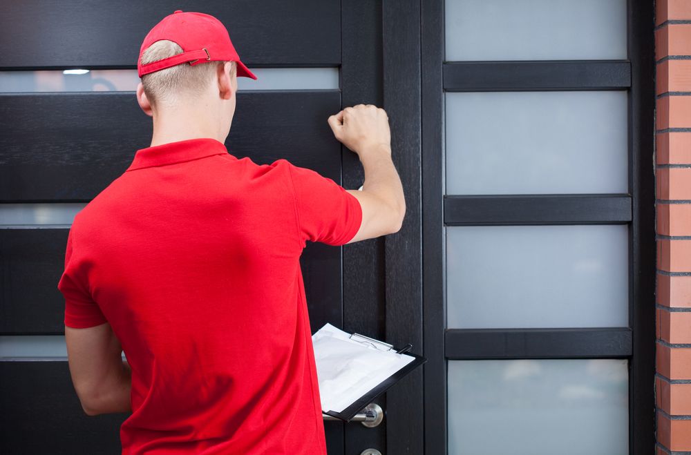 Back view of a delivery man knocking on the clients door.jpeg