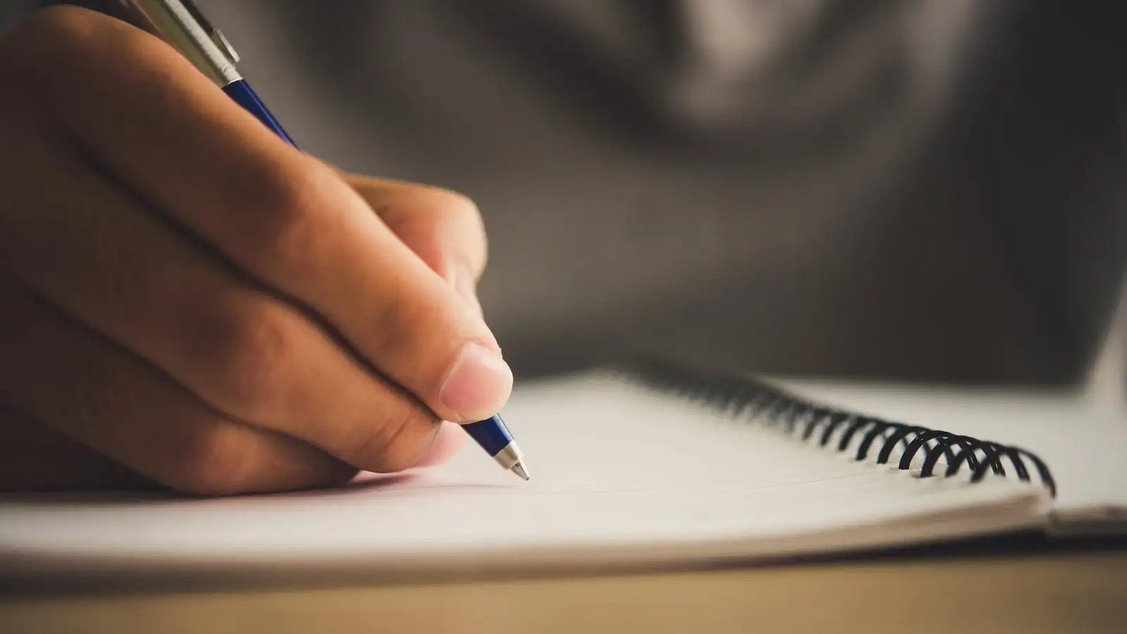 penna tra le dita scrive su un foglio di carta microcopy.jpg