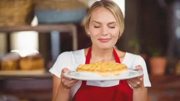 Pretty waitress smelling a plate of cake at the coffee shop.jpeg