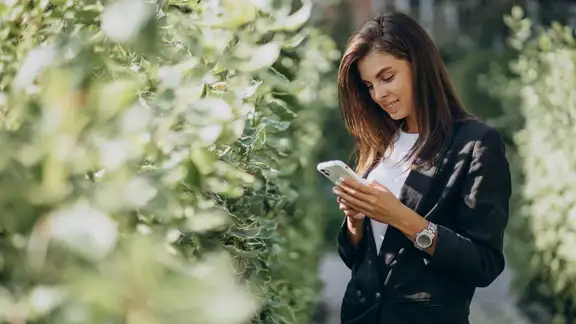 donna con cellulare in mano in un parco-1.jpg