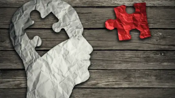 Puzzle head brain concept as a human face profile made from crumpled white paper with a jigsaw piece cut out on a rustic old wood background as a mental health symbol..jpeg