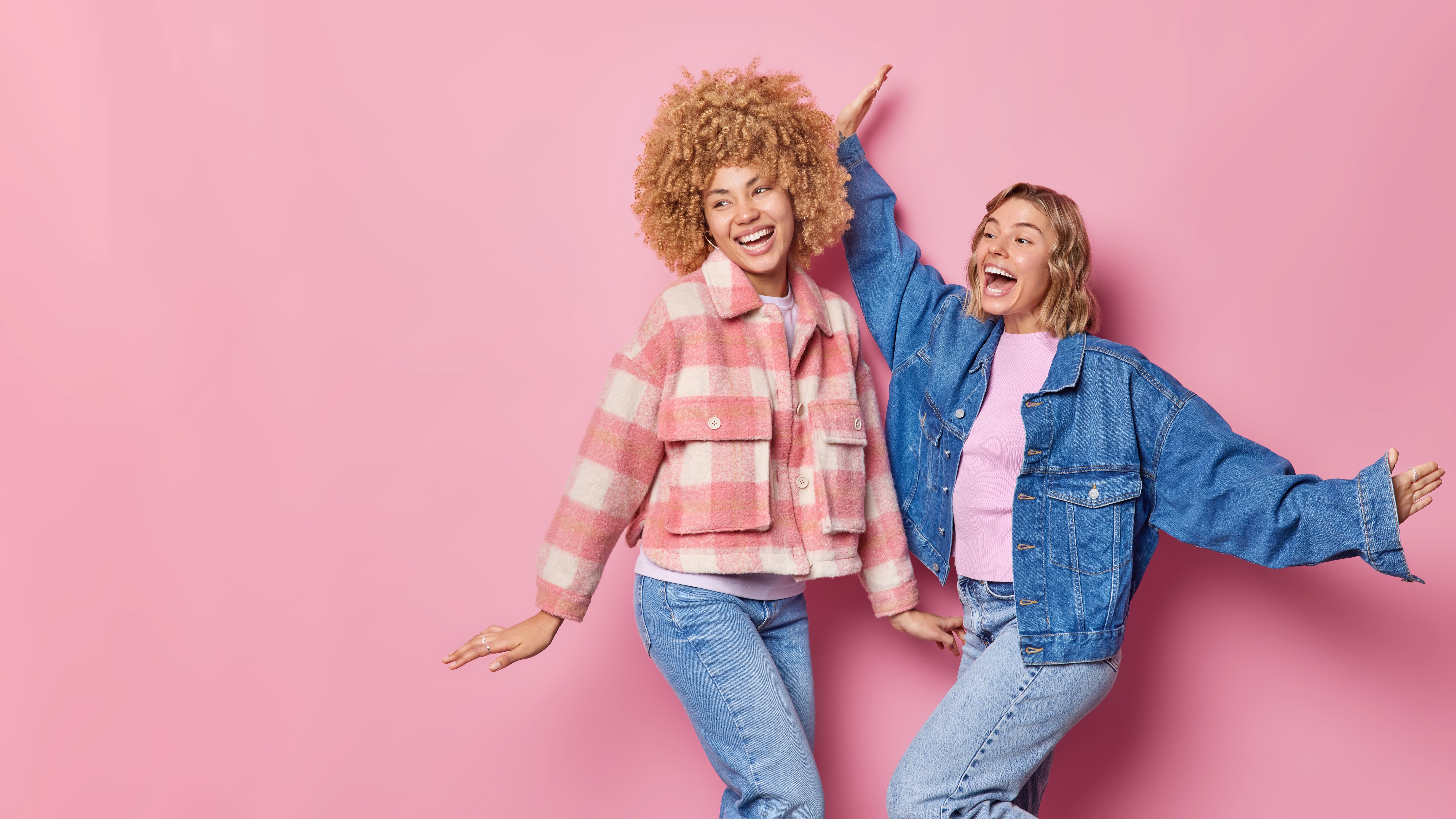 indoor-shot-of-happy-carefree-beautiful-young-women-wear-fashionable-clothes-dance-with-arms-raised-up-move-against-pink-background-blank-copy-space-for-your-promotional-content-lets-party.jpg