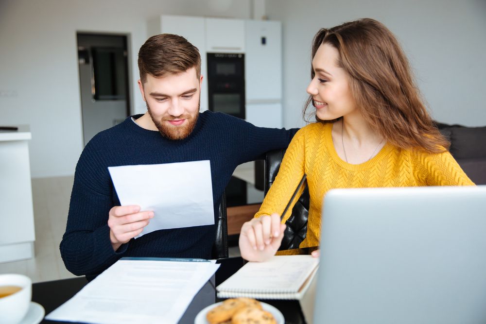 Happy young couple calculating bills at home.jpeg