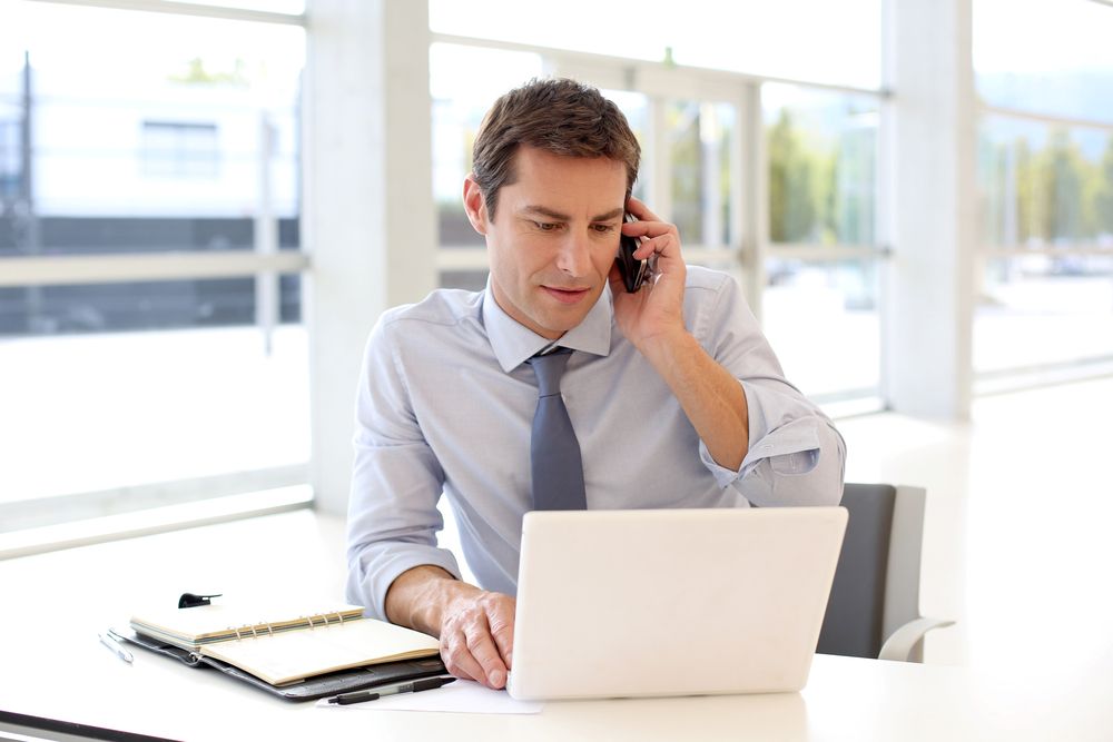 Portrait of businessman talking on mobile phone in office.jpeg