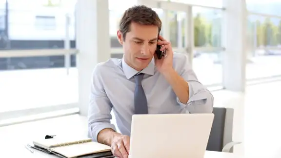 Portrait of businessman talking on mobile phone in office.jpeg