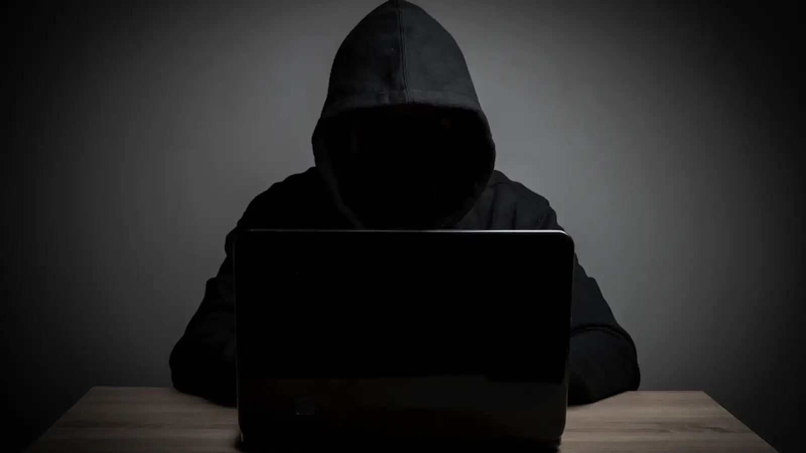 uomo incapucciato vestito di nero davanti al pc.jpg