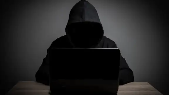 uomo incapucciato vestito di nero davanti al pc.jpg