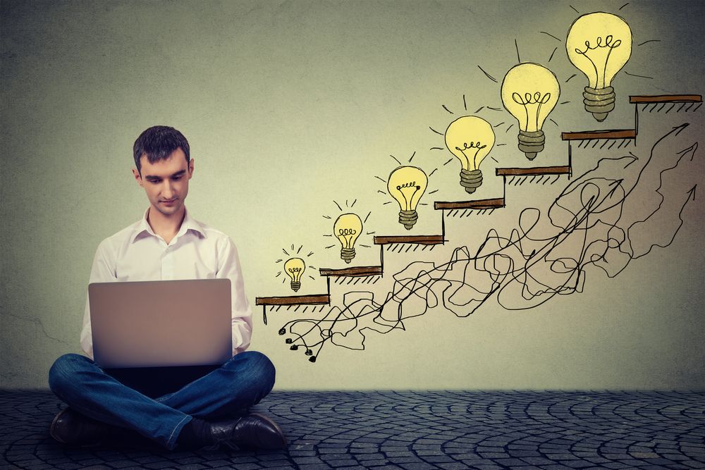 Happy young man entrepreneur working on computer sitting on a floor in his office successful in increasing internet website traffic. Promotion%2c company growth concept. Isolated on gray wall background.jpeg