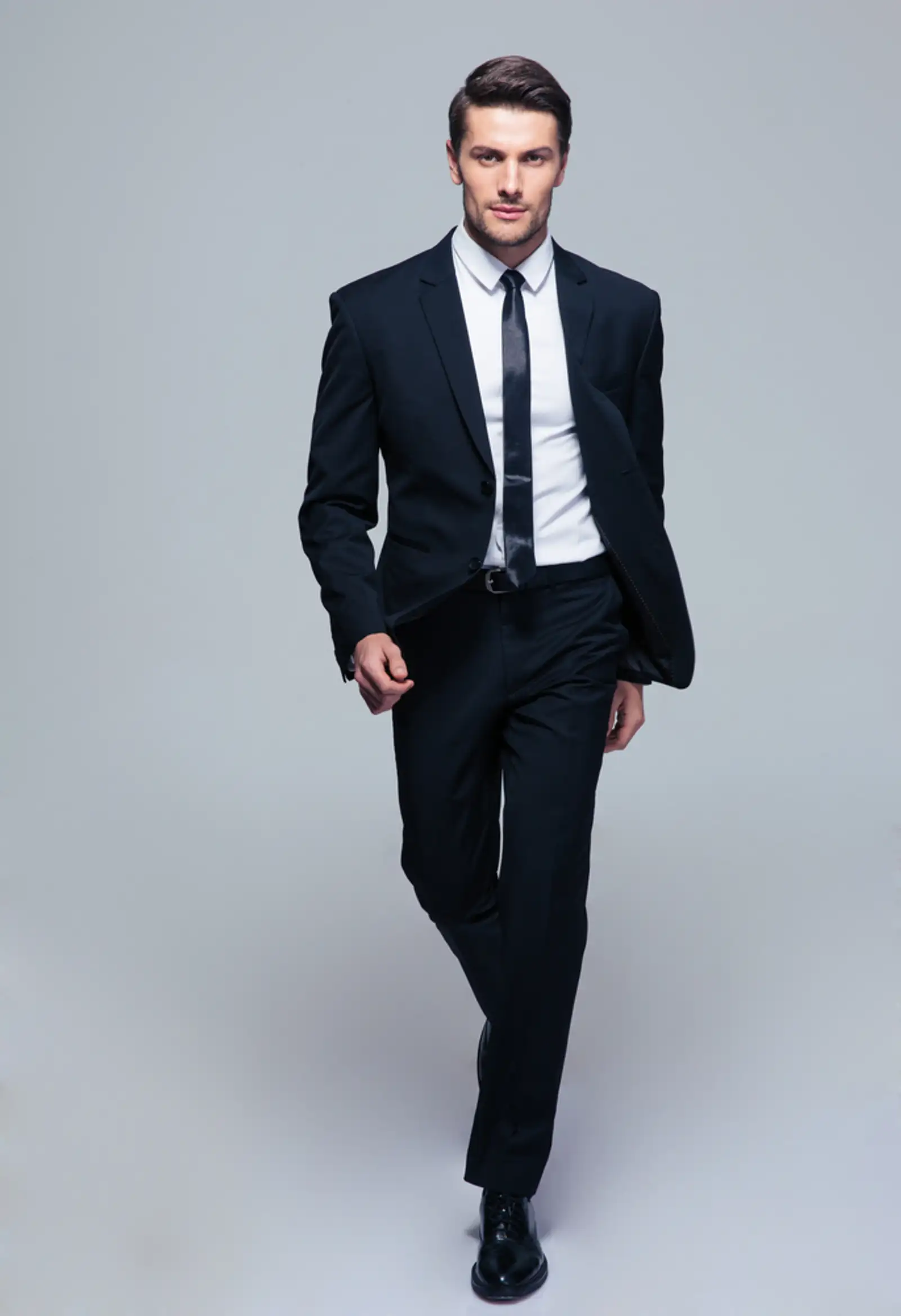 Full length portrait of a fashion male model over gray background. Looking at camera.jpeg