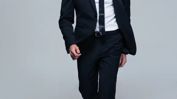 Full length portrait of a fashion male model over gray background. Looking at camera.jpeg