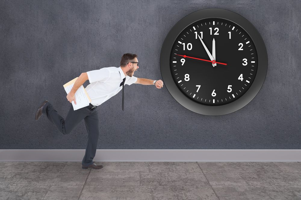 Geeky young businessman running late against grey room.jpeg