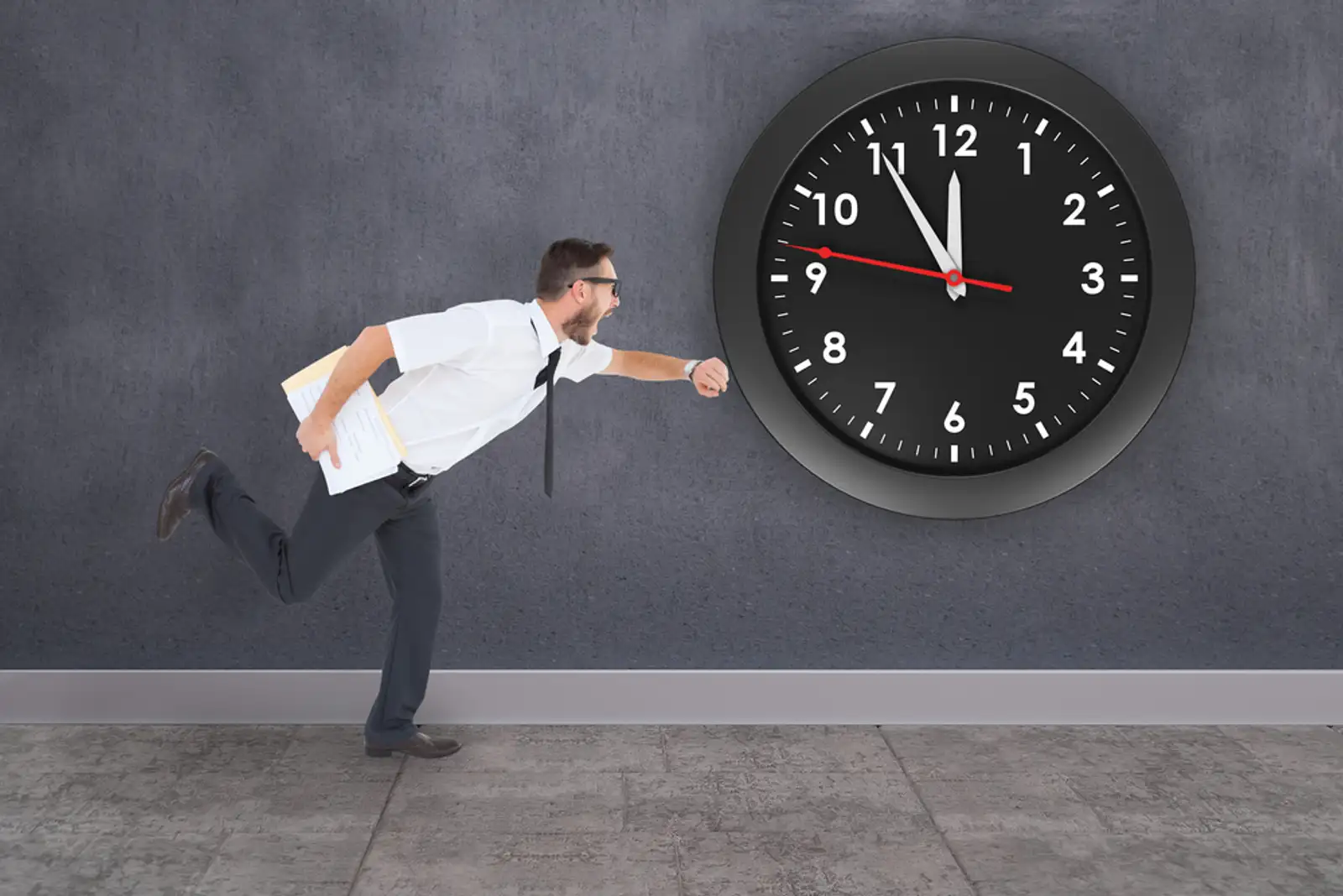 Geeky young businessman running late against grey room.jpeg