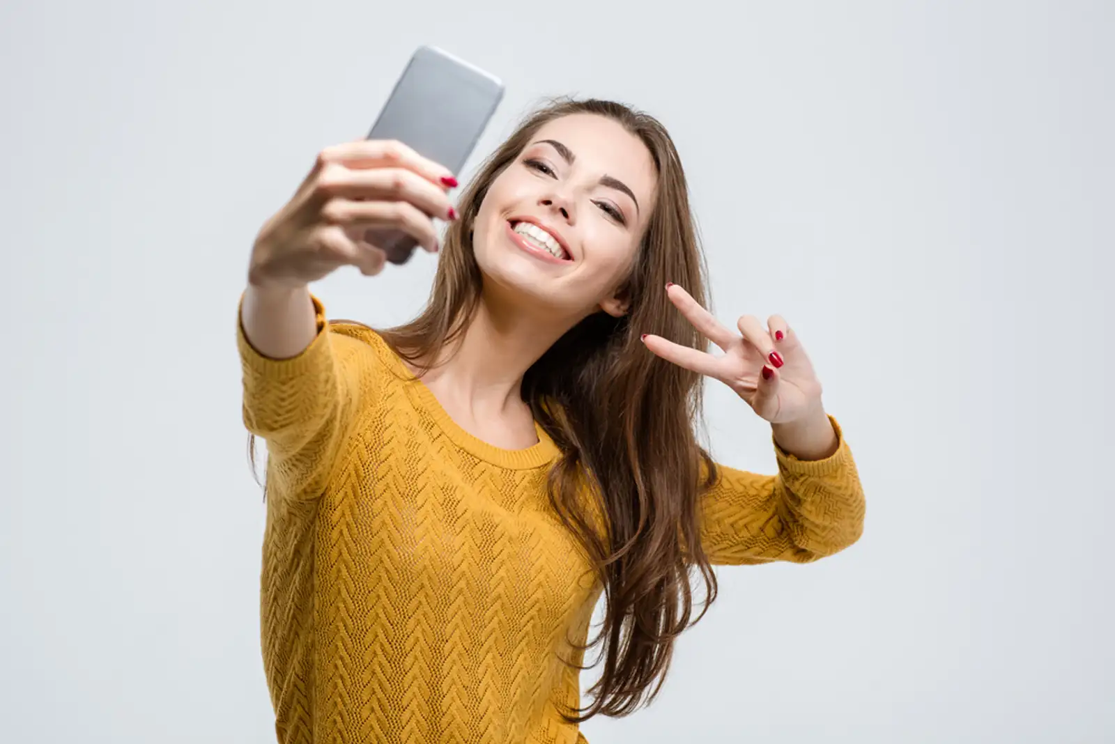 Portrait of a smiling cute woman making selfie photo on smartphone isolated on a white background.jpeg