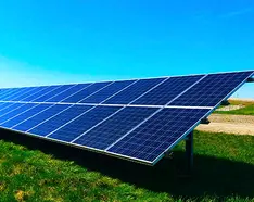 solar array on green grass below a blue sky