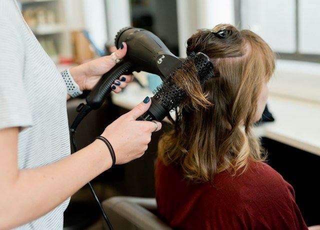 Stylist blow-drying a client's hair in a salon