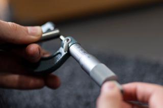 Hands using a measuring tool to measure a metal part 