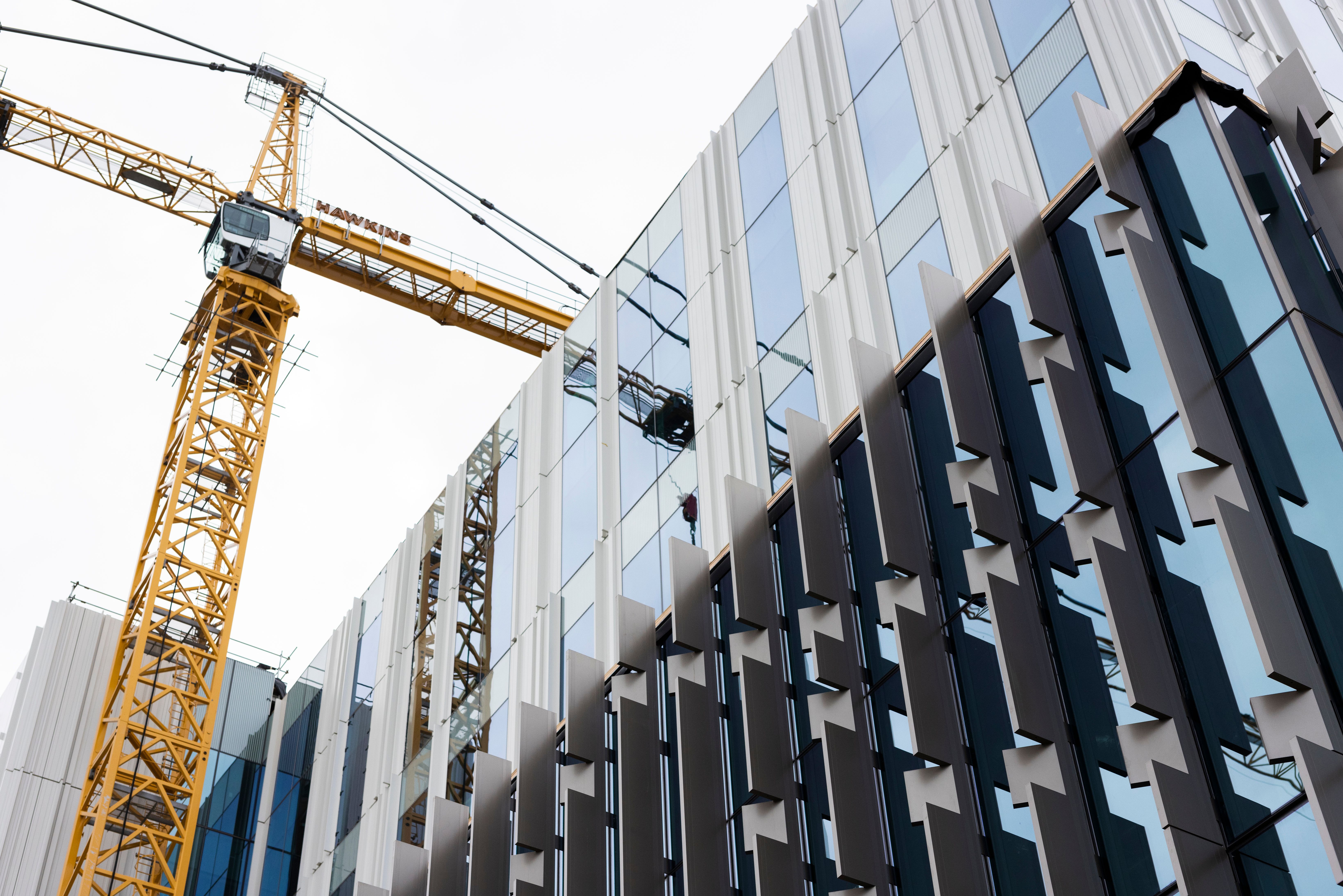 Glass and steel building facade with a yellow crane near the building