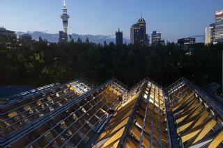 Auckland city scape at night with steel and wooden roof framing in the foreground 