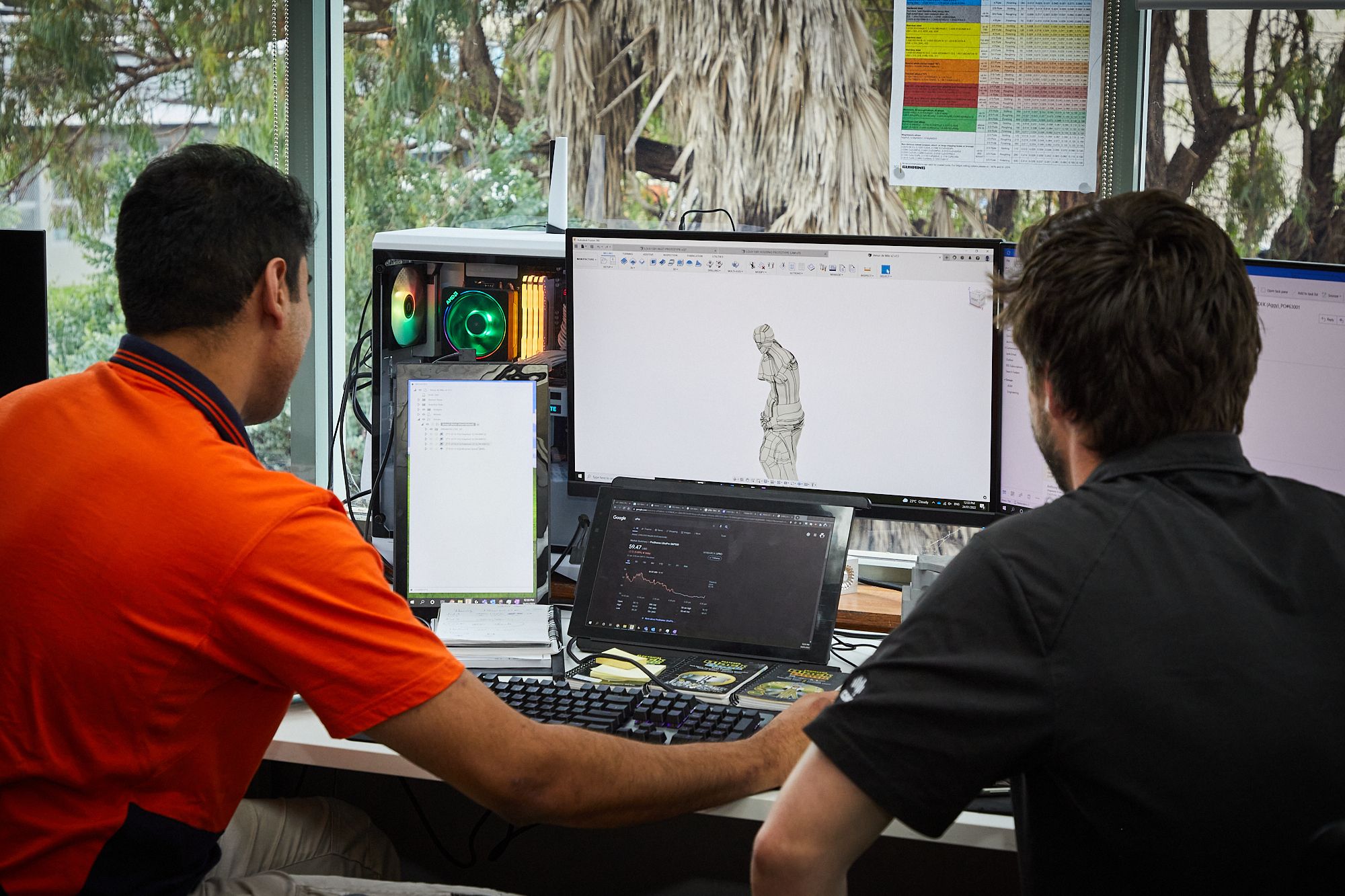 Two engineers sitting in front of computer with CAD model on the screen 