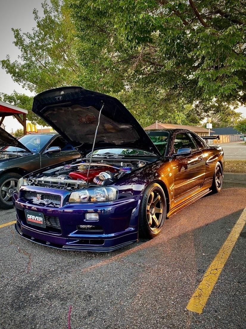 A purple Nissan Skyline with bonnet open in a carpark 