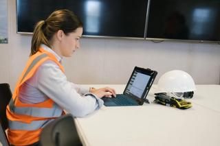 Woman in high-vis vest at a desk using Bluebeam software on a tablet 