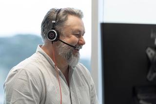 Cadpro support person with a headset on, speaking to someone and smiling as he provides technical support