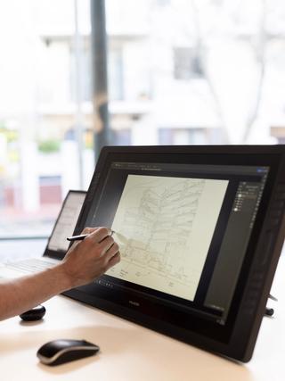 Hand using stylus to mark up architectural drawing on a stand up tablet screen