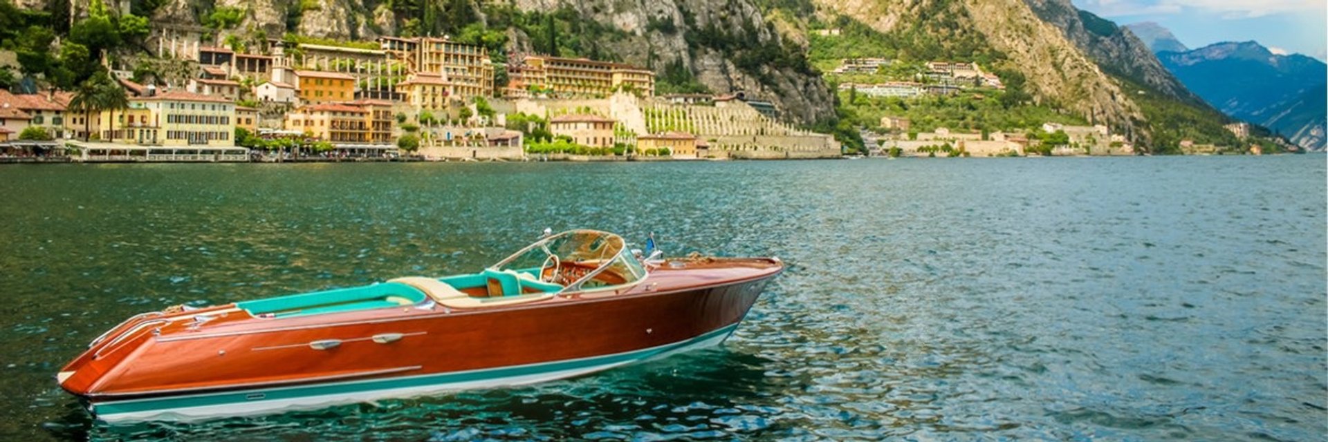 Classic Riva speedboat cruising on Lake Como with mountains and villas in the background