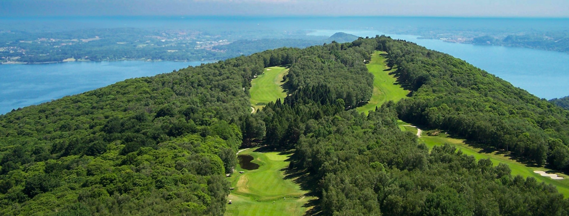 Panoramic view of a championship golf course overlooking the Italian Lakes with alpine backdrop