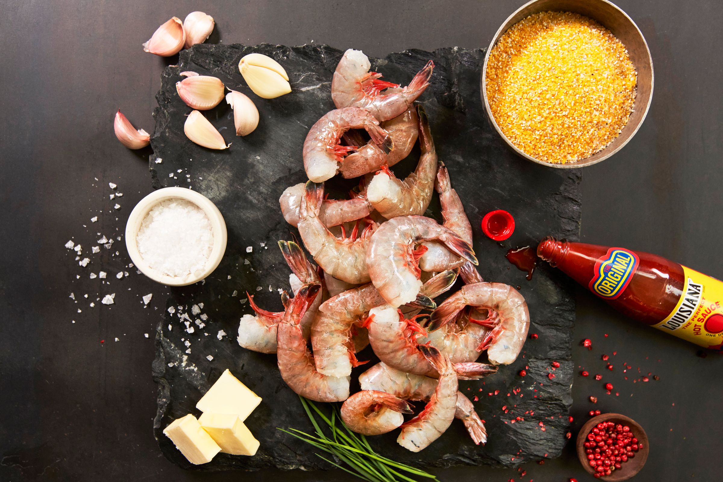 a pile of shrimp sitting on top of a cutting board surrounded by ingredients .