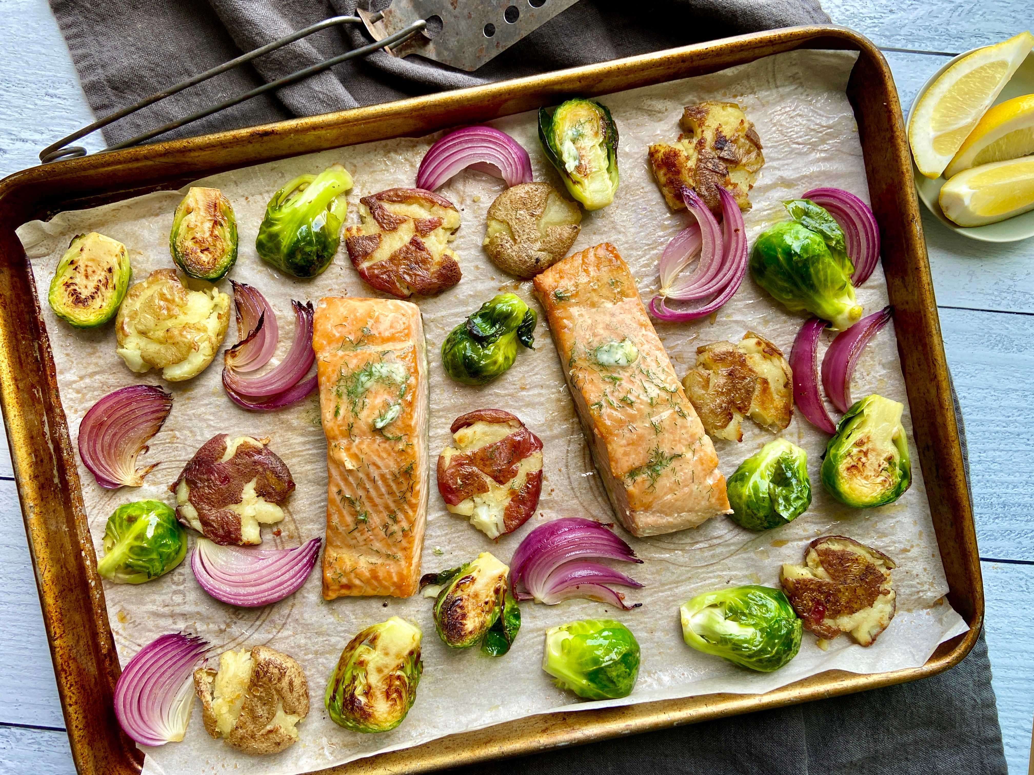 sheet pan with potatoes, onions, Brussels sprouts and salmon on a table