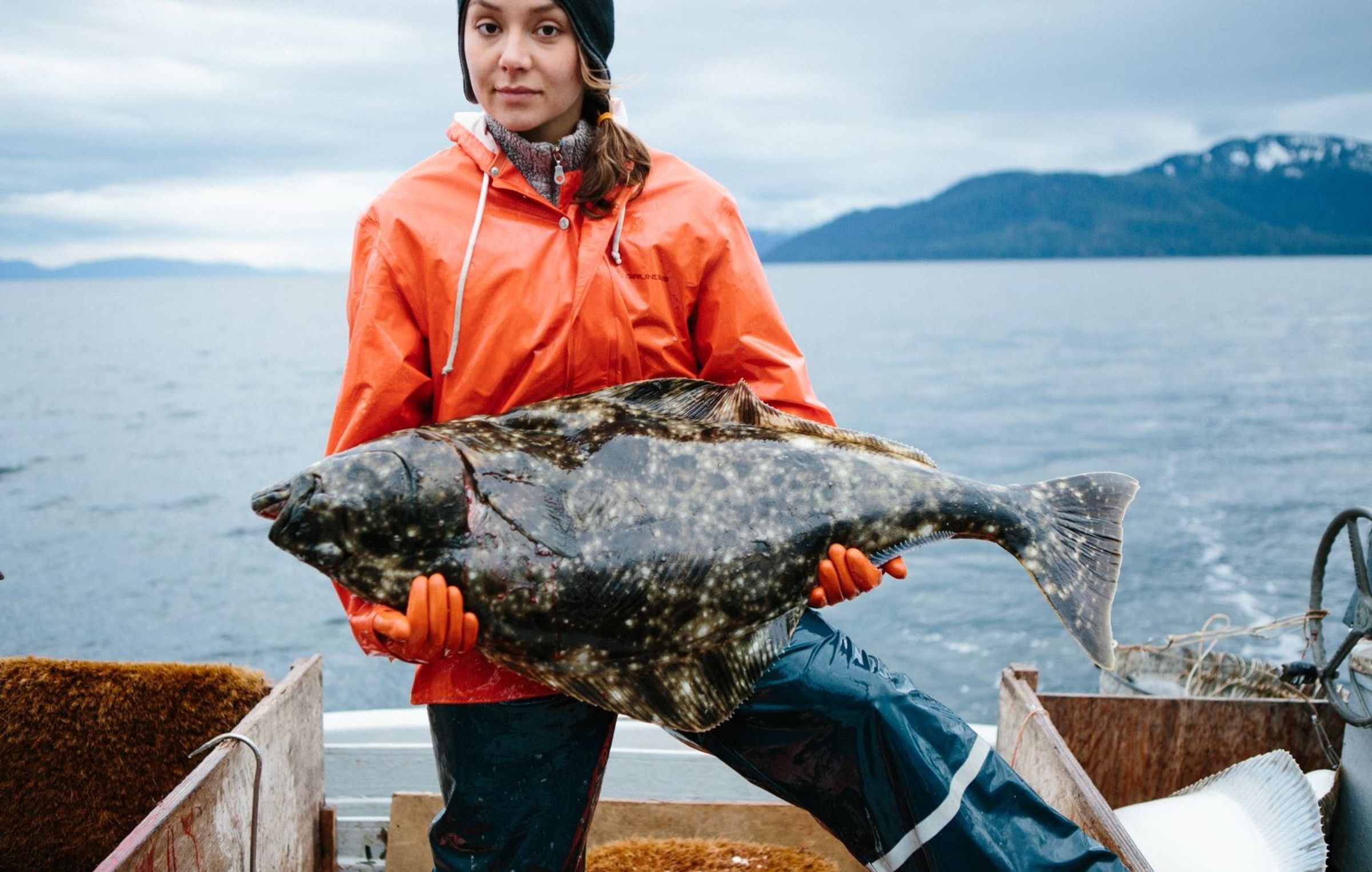 a woman is holding a large fish on a boat .