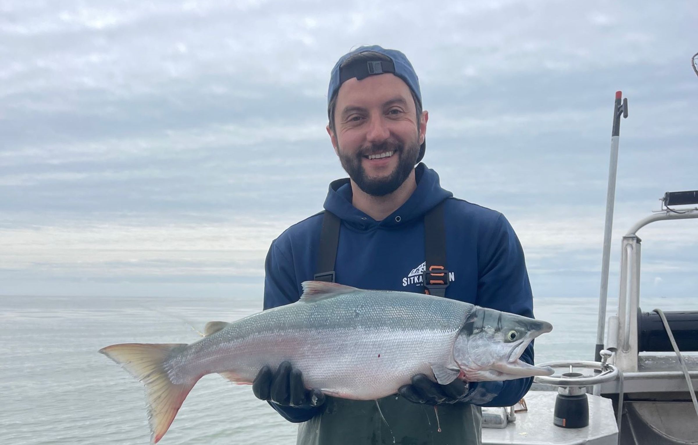 a man is holding a large fish on a boat .